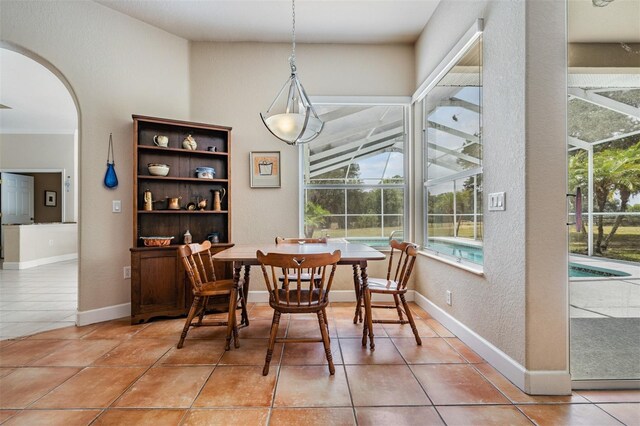 dining space with light tile patterned floors, baseboards, and arched walkways