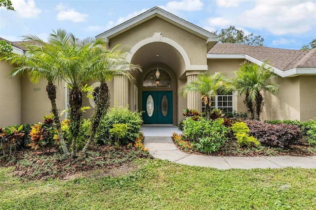 property entrance featuring roof with shingles and stucco siding