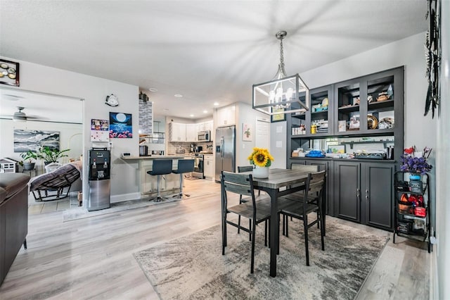 dining area featuring ceiling fan with notable chandelier and light hardwood / wood-style floors