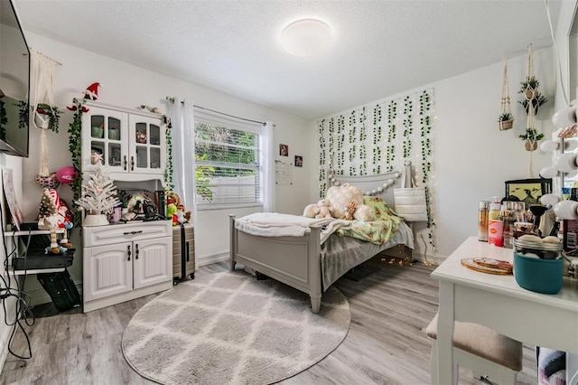 bedroom with light hardwood / wood-style floors and a textured ceiling