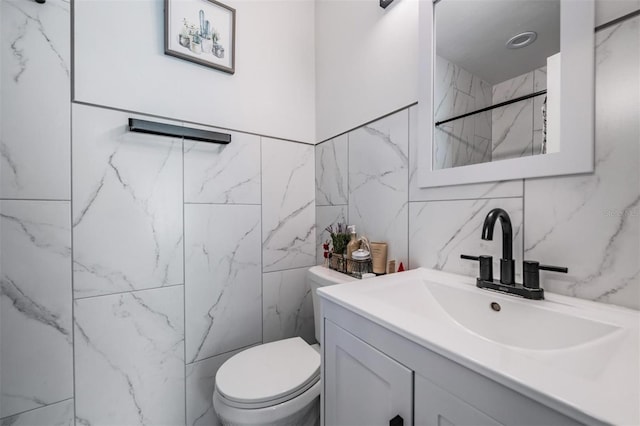 bathroom with toilet, tile walls, walk in shower, and vanity