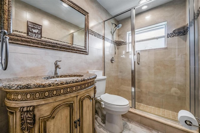 bathroom featuring vanity, a shower with shower door, tile walls, and toilet