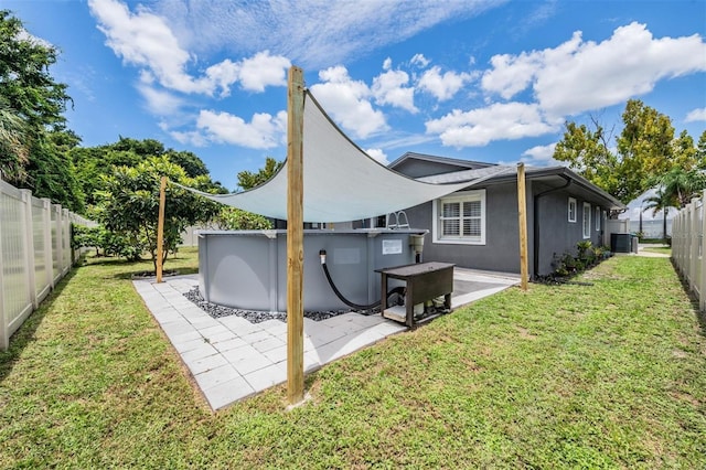 rear view of house featuring a patio area, a swimming pool, a lawn, and central air condition unit