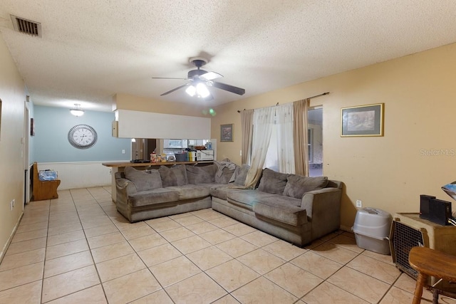 living room with ceiling fan, a textured ceiling, and light tile patterned floors