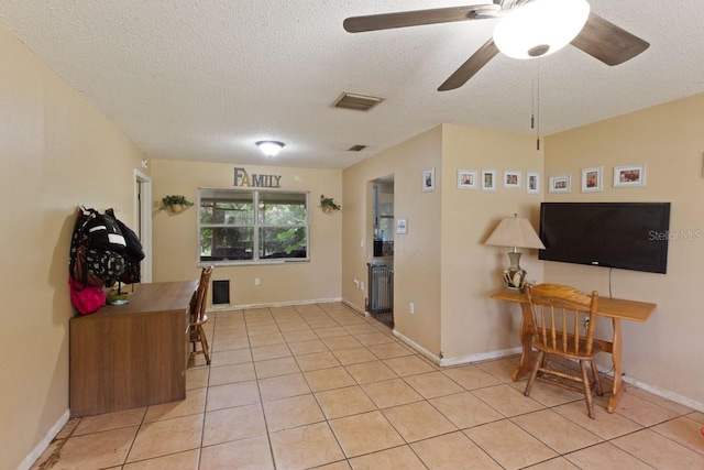 interior space featuring a textured ceiling, light tile patterned floors, and ceiling fan