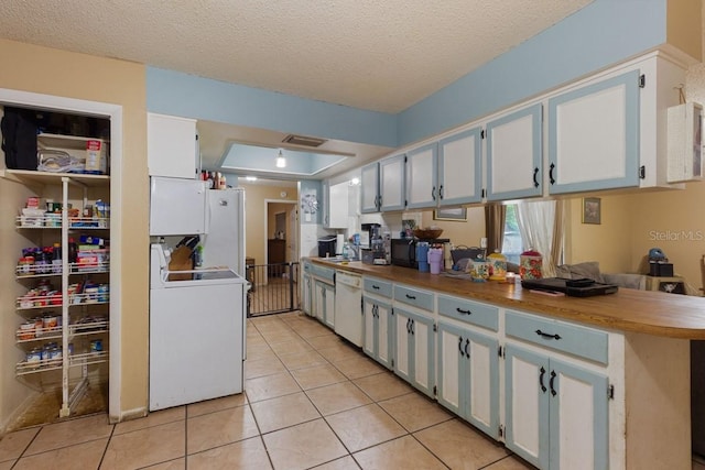 kitchen with white cabinetry, a textured ceiling, light tile patterned floors, sink, and white appliances