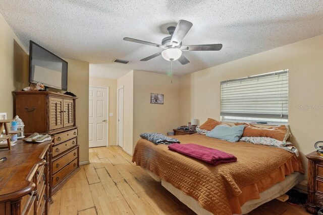 bedroom with a textured ceiling, light hardwood / wood-style floors, and ceiling fan