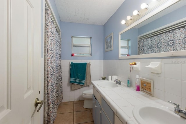 bathroom featuring tile walls, vanity, a textured ceiling, tile patterned flooring, and toilet