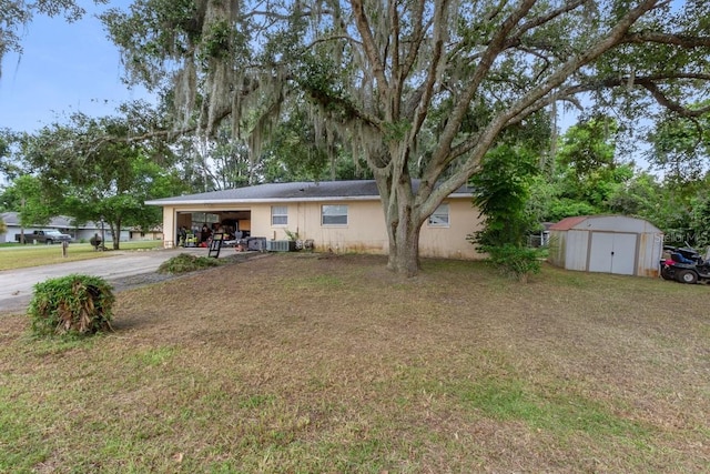 view of front of house featuring a storage unit, an outbuilding, driveway, a front lawn, and an attached garage