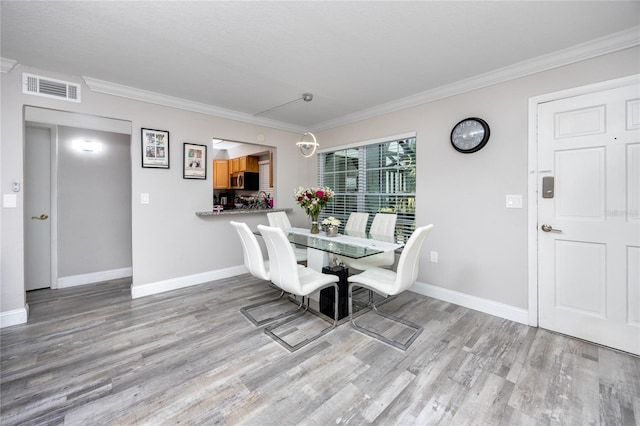 dining room featuring ornamental molding and light wood-type flooring