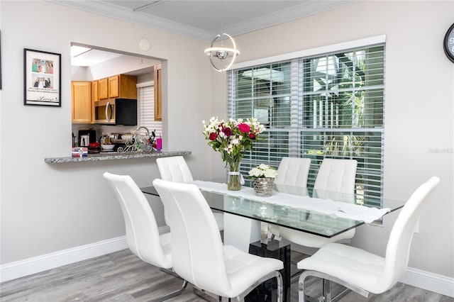 dining room with light hardwood / wood-style flooring, ornamental molding, a chandelier, and a healthy amount of sunlight