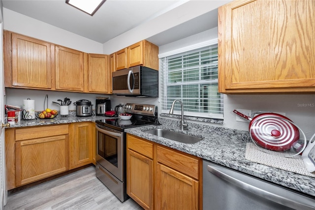 kitchen featuring sink, light stone counters, light hardwood / wood-style flooring, and stainless steel appliances