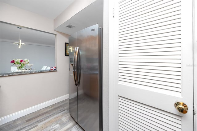 kitchen featuring ornamental molding, light hardwood / wood-style floors, and stainless steel refrigerator with ice dispenser