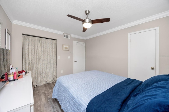 bedroom featuring ceiling fan, a textured ceiling, crown molding, and light wood-type flooring