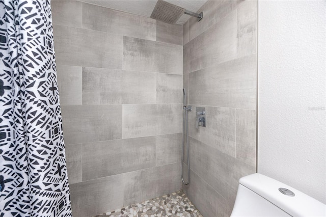 bathroom featuring a tile shower and toilet