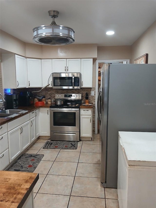 kitchen with backsplash, stainless steel appliances, sink, white cabinets, and butcher block counters