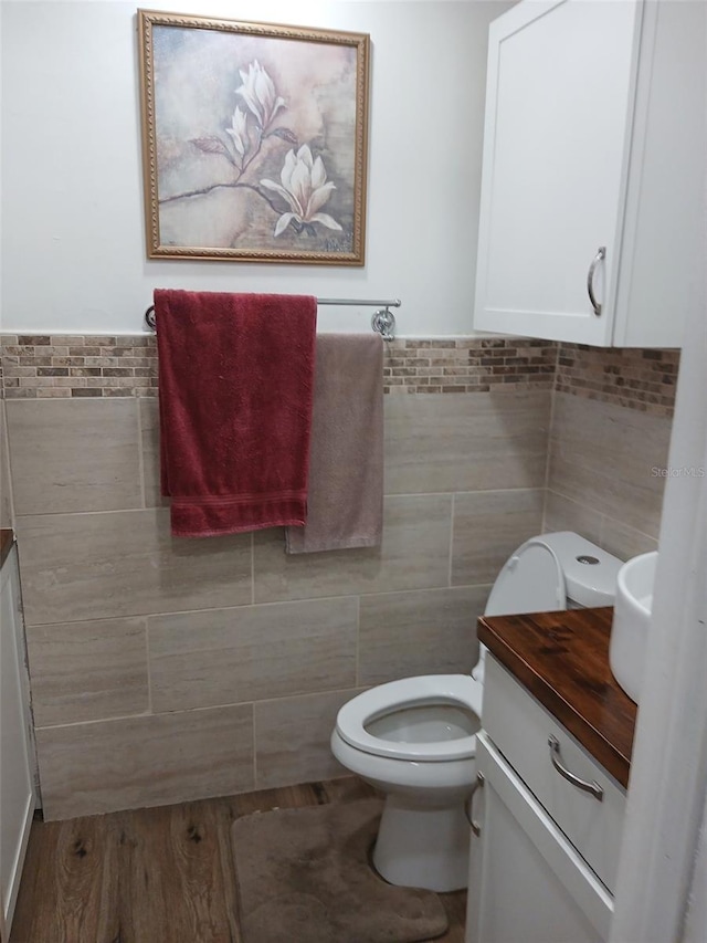 bathroom featuring vanity, hardwood / wood-style flooring, toilet, and tile walls