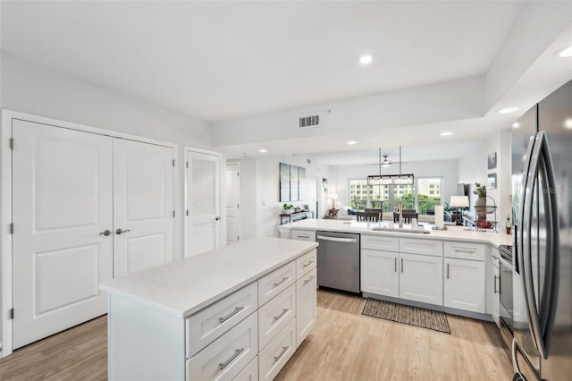 kitchen featuring a kitchen island, white cabinetry, sink, kitchen peninsula, and stainless steel appliances