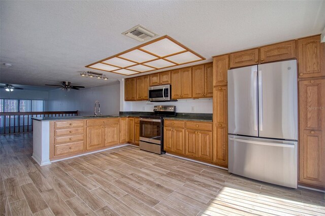 kitchen with stainless steel appliances, sink, light hardwood / wood-style flooring, and a textured ceiling