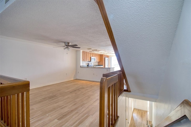 stairs with ceiling fan, wood-type flooring, and a textured ceiling