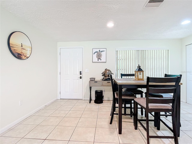 dining space with light tile patterned floors and a textured ceiling