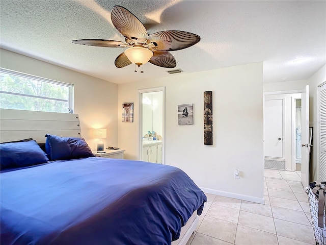 bedroom featuring light tile patterned floors, ensuite bath, a textured ceiling, and ceiling fan