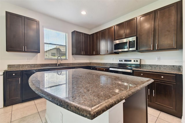 kitchen with light tile patterned flooring, stainless steel appliances, sink, and a kitchen island