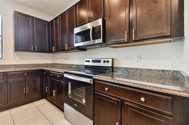 kitchen featuring dark stone countertops, light tile patterned floors, dark brown cabinets, and stainless steel appliances