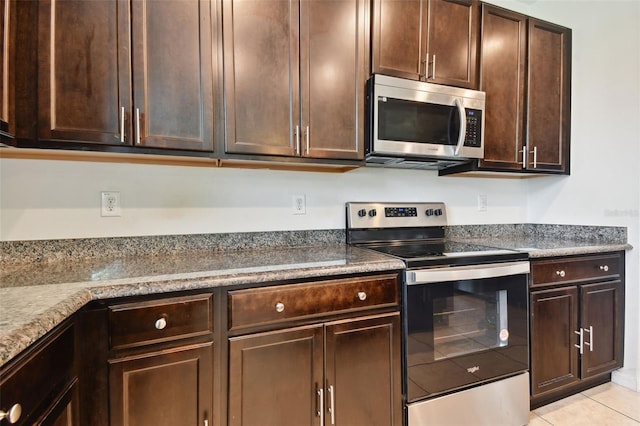 kitchen with light tile patterned flooring, appliances with stainless steel finishes, light stone counters, and dark brown cabinets