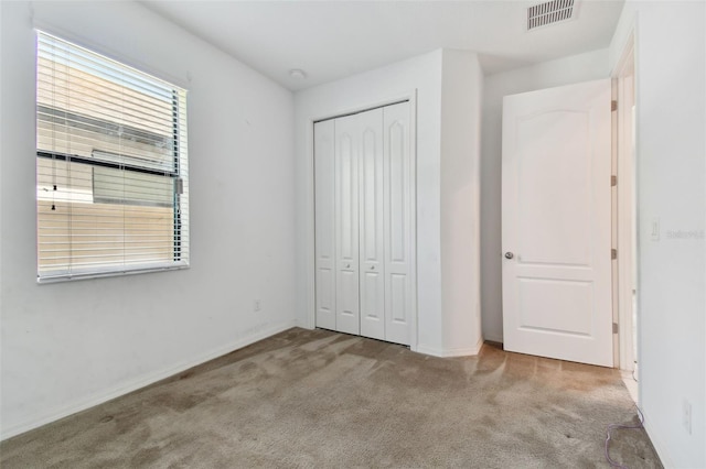 unfurnished bedroom featuring light colored carpet and a closet