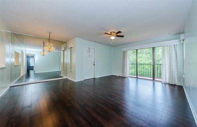 spare room featuring dark hardwood / wood-style flooring, ceiling fan with notable chandelier, and a textured ceiling