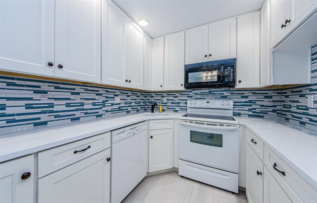 kitchen with backsplash, white appliances, light tile patterned floors, and white cabinets