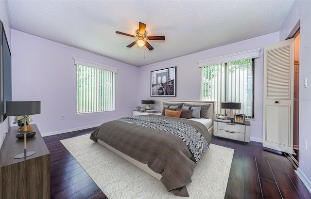 bedroom with multiple windows, ceiling fan, a textured ceiling, and dark hardwood / wood-style flooring