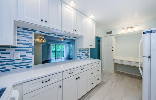 kitchen featuring white cabinetry, decorative backsplash, white fridge, and a textured ceiling