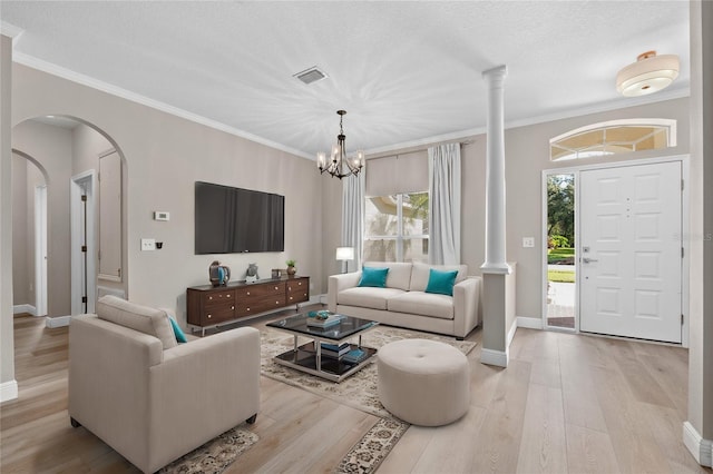 living room featuring light wood-type flooring, a textured ceiling, a notable chandelier, and crown molding