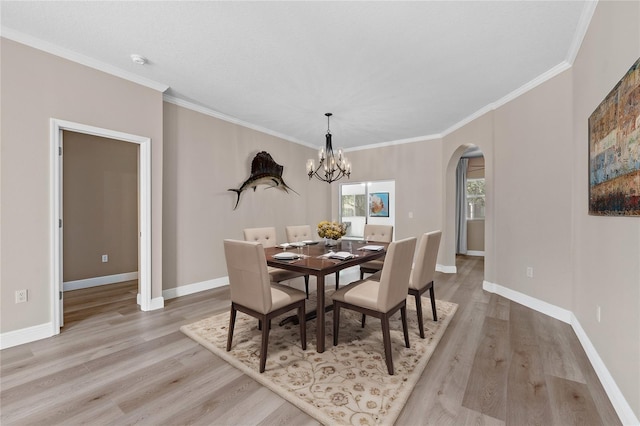 dining space featuring light hardwood / wood-style flooring, crown molding, and a notable chandelier