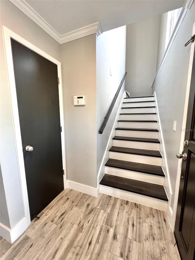 stairway with light hardwood / wood-style floors and ornamental molding