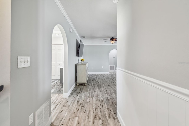 hallway with light hardwood / wood-style floors and ornamental molding