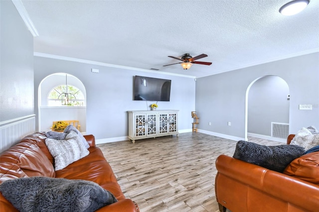 living room with crown molding, ceiling fan, light hardwood / wood-style flooring, and a textured ceiling