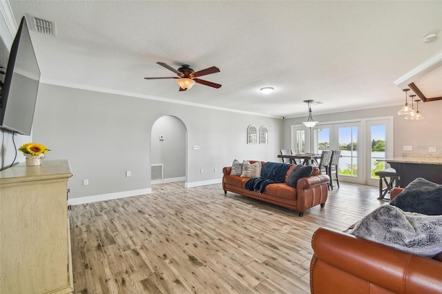 living room with ceiling fan with notable chandelier, light hardwood / wood-style floors, a textured ceiling, and ornamental molding