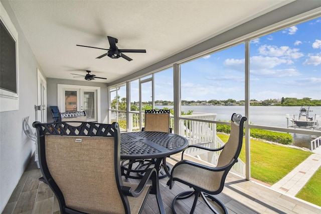 sunroom / solarium with a water view and ceiling fan