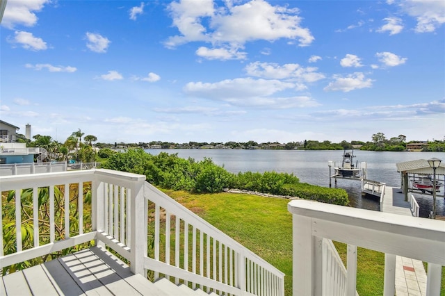 wooden deck with a boat dock, a lawn, and a water view