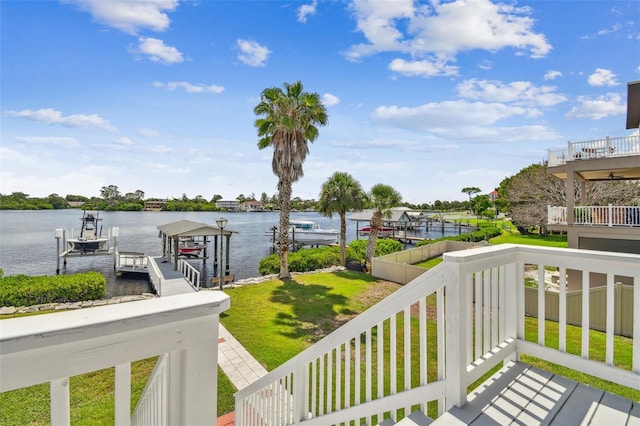 wooden deck with a boat dock, a water view, and a lawn