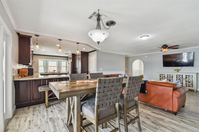 dining space featuring ornamental molding, a textured ceiling, ceiling fan, and light wood-type flooring