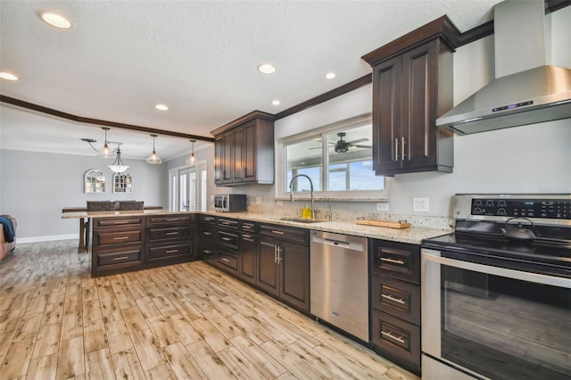 kitchen with light hardwood / wood-style flooring, stainless steel appliances, hanging light fixtures, wall chimney exhaust hood, and dark brown cabinetry