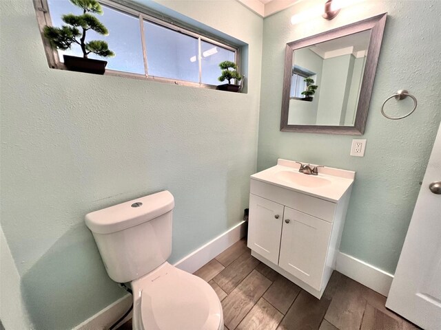 bathroom featuring wood-type flooring, toilet, and vanity