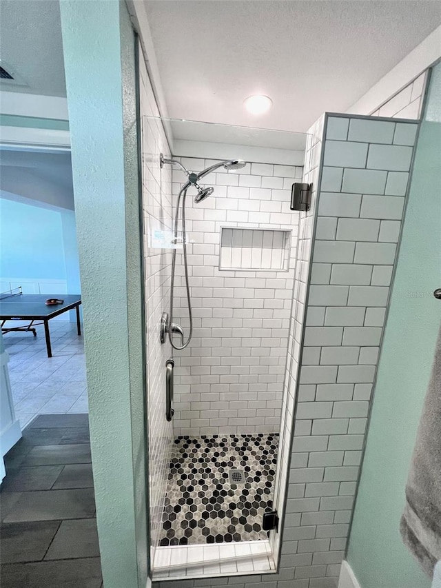 bathroom with tiled shower and tile patterned flooring