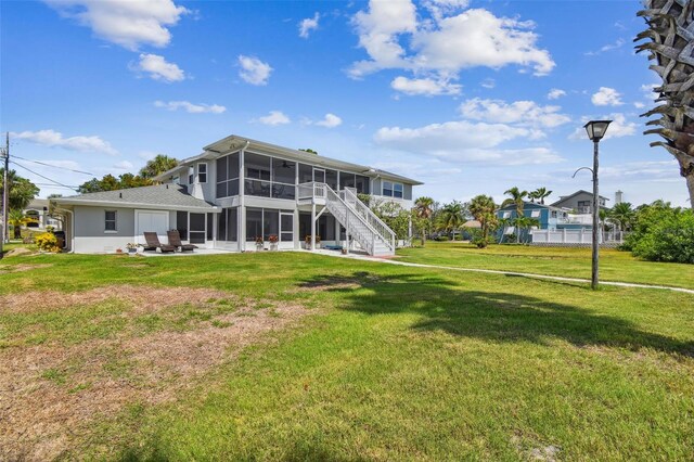 back of property featuring a yard, a sunroom, and a patio area