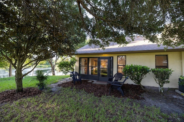 rear view of property featuring a water view, a yard, and a sunroom