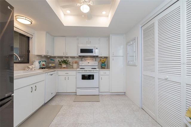 kitchen featuring white cabinetry, white appliances, a raised ceiling, and sink